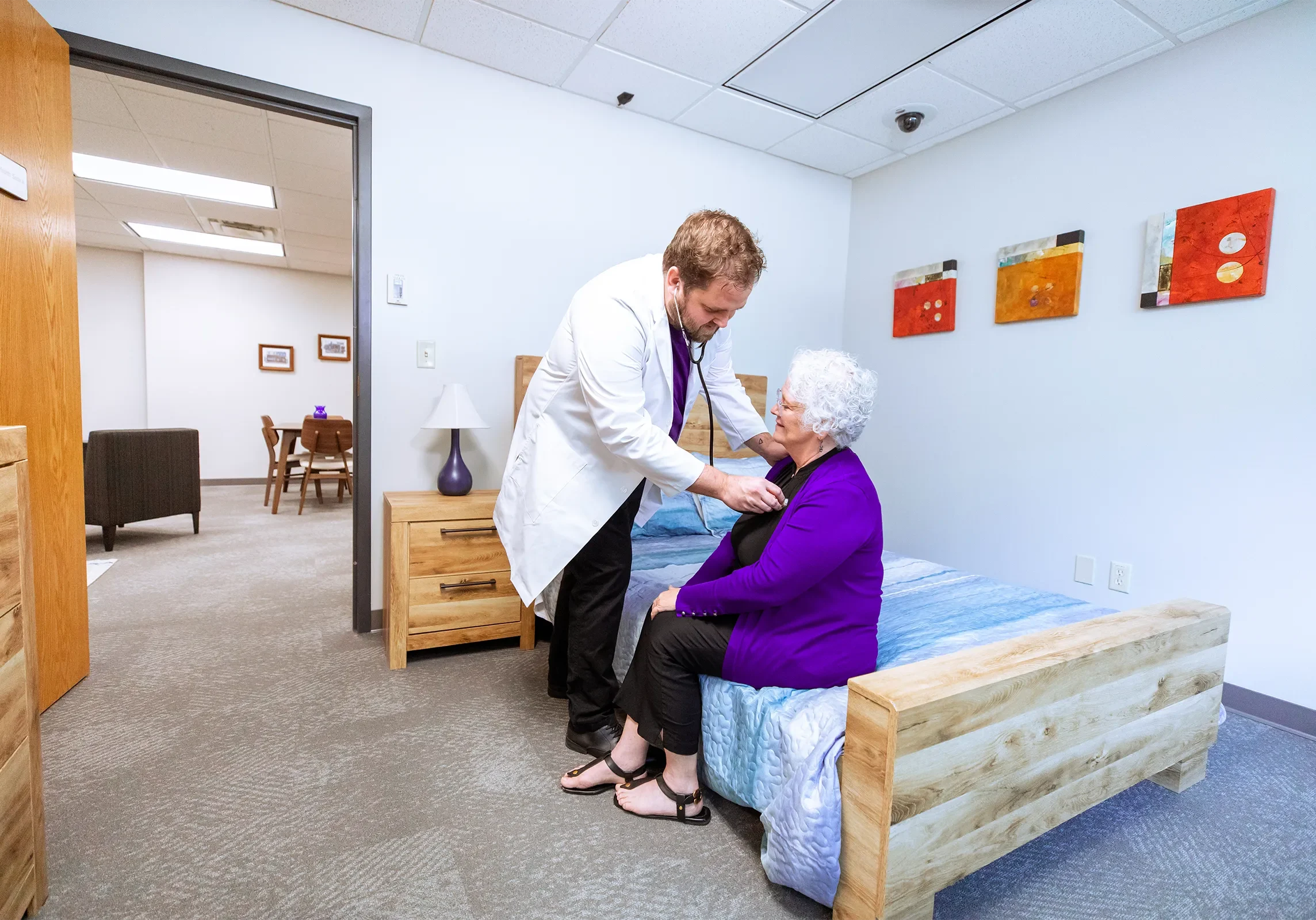 DMU32_SIM_Home_Health_Care_4615 A person in a white coat checks the pulse of a simulated patient in the Home Health Care Lab.